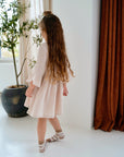 girl wearing cream pink organic cotton muslin dress back view