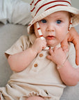 baby wearing beige rib romper and matching hat close up