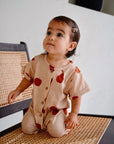 child wearing beige cotton playsuit with red apple and pear print