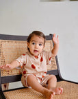 child wearing beige cotton playsuit with red apple and pear print