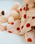 Child wearing beige cotton shorts with red fruit print while sitting