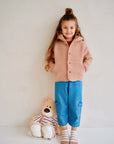 Child wearing blue cotton denim pants with light pink wool jacket