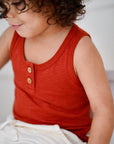 Child wearing cream white cotton muslin shorts with red tank top