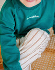 child wearing green fleece sweatshirt with striped pants close up