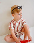 child wearing white cotton playsuit with red stripes close up