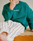 Child wearing white cotton terry pants with green sweatshirt