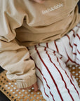Child wearing white cotton terry pants with red stripes closeup