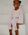 Child wearing white cotton terry pants with red stripes while sitting