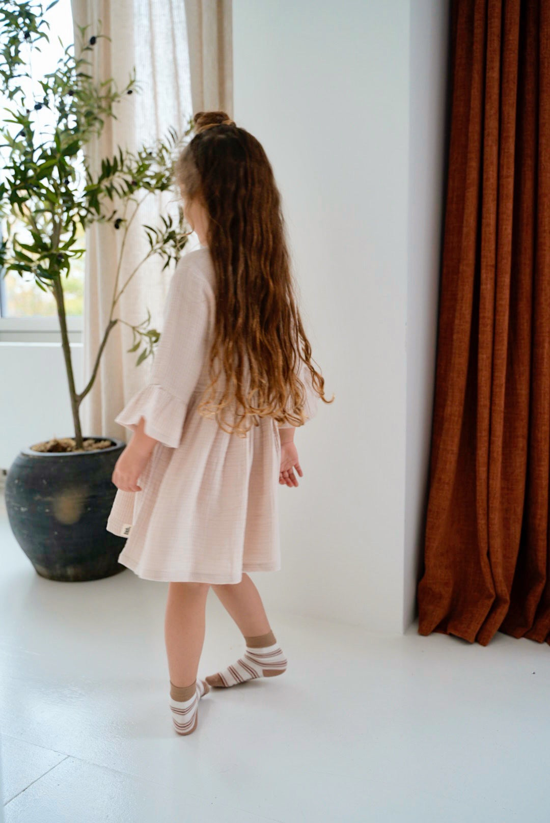 girl wearing cream pink organic cotton muslin dress back view