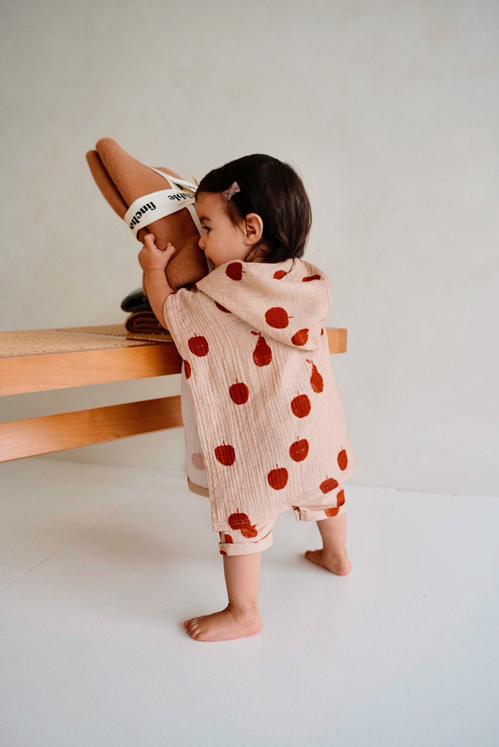Toddler wearing beige hooded poncho towel with red fruit print back view