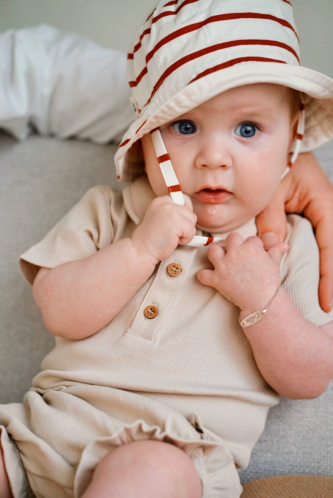 baby wearing beige rib romper and matching hat close up