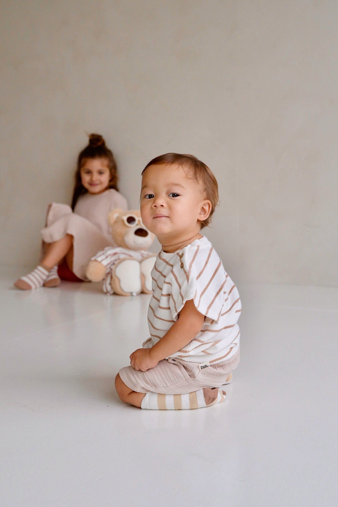 Child wearing beige cotton muslin shorts while sitting