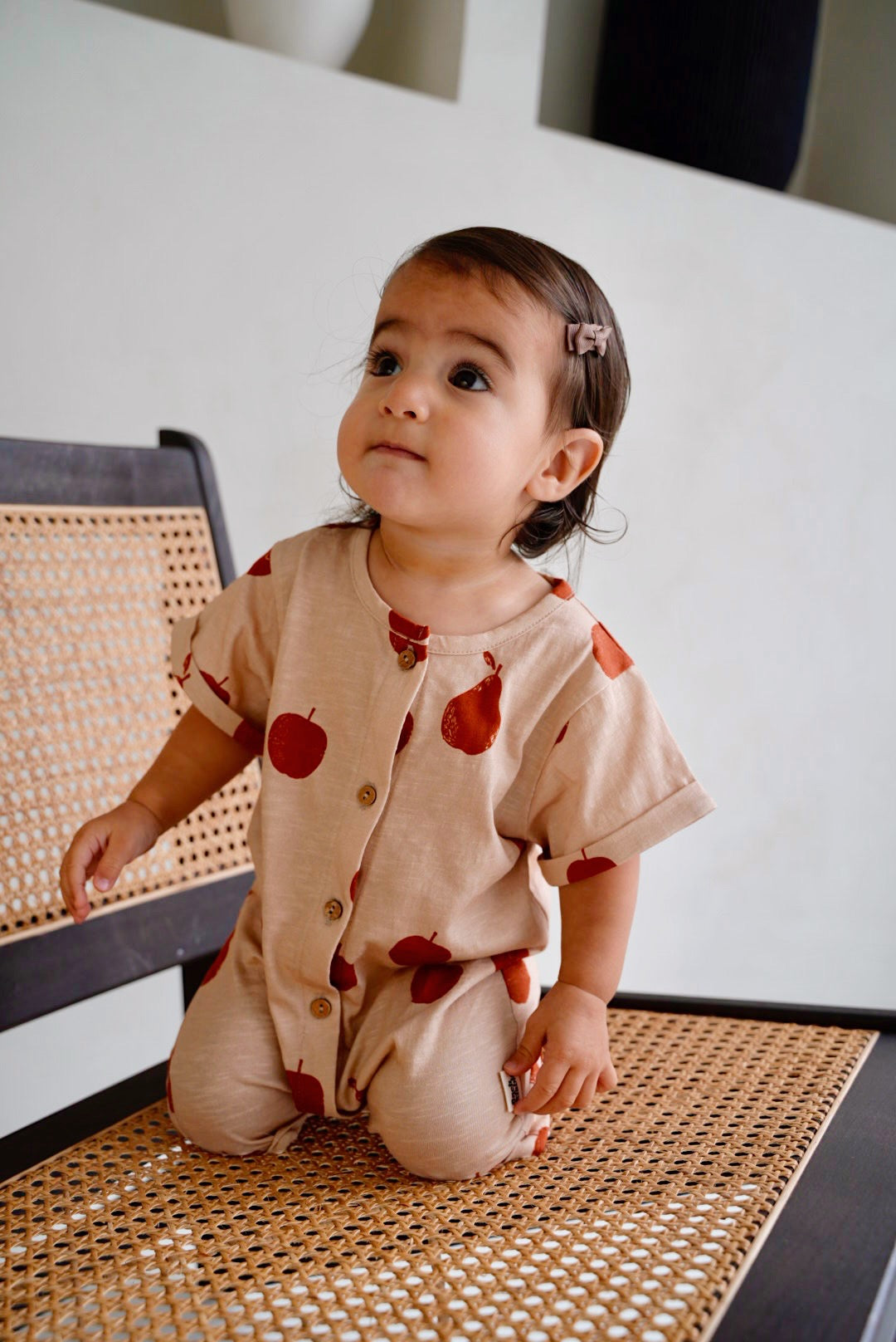 child wearing beige cotton playsuit with red apple and pear print