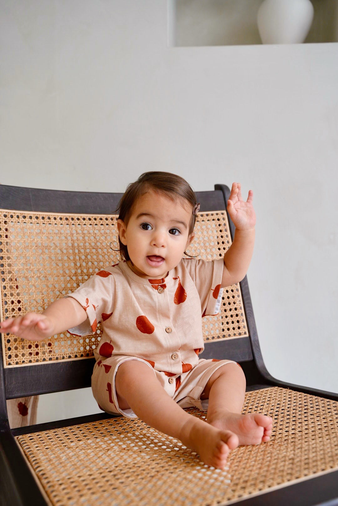child wearing beige cotton playsuit with red apple and pear print