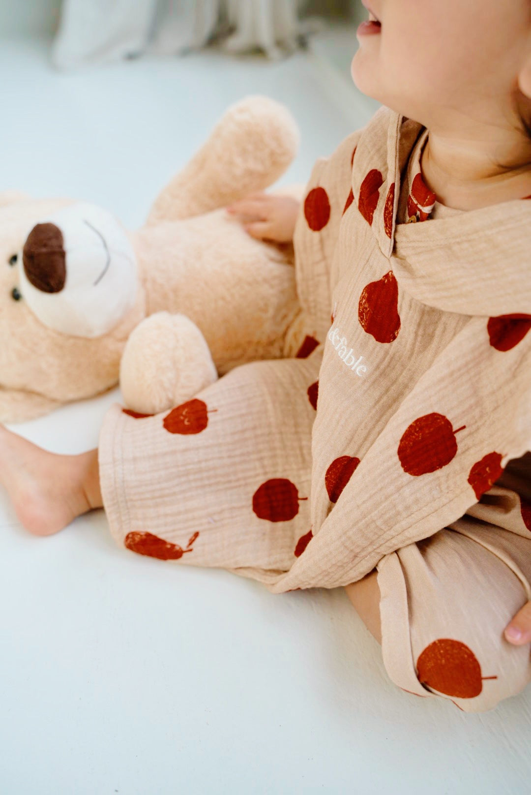 Child wearing beige cotton shorts with red fruit print while sitting
