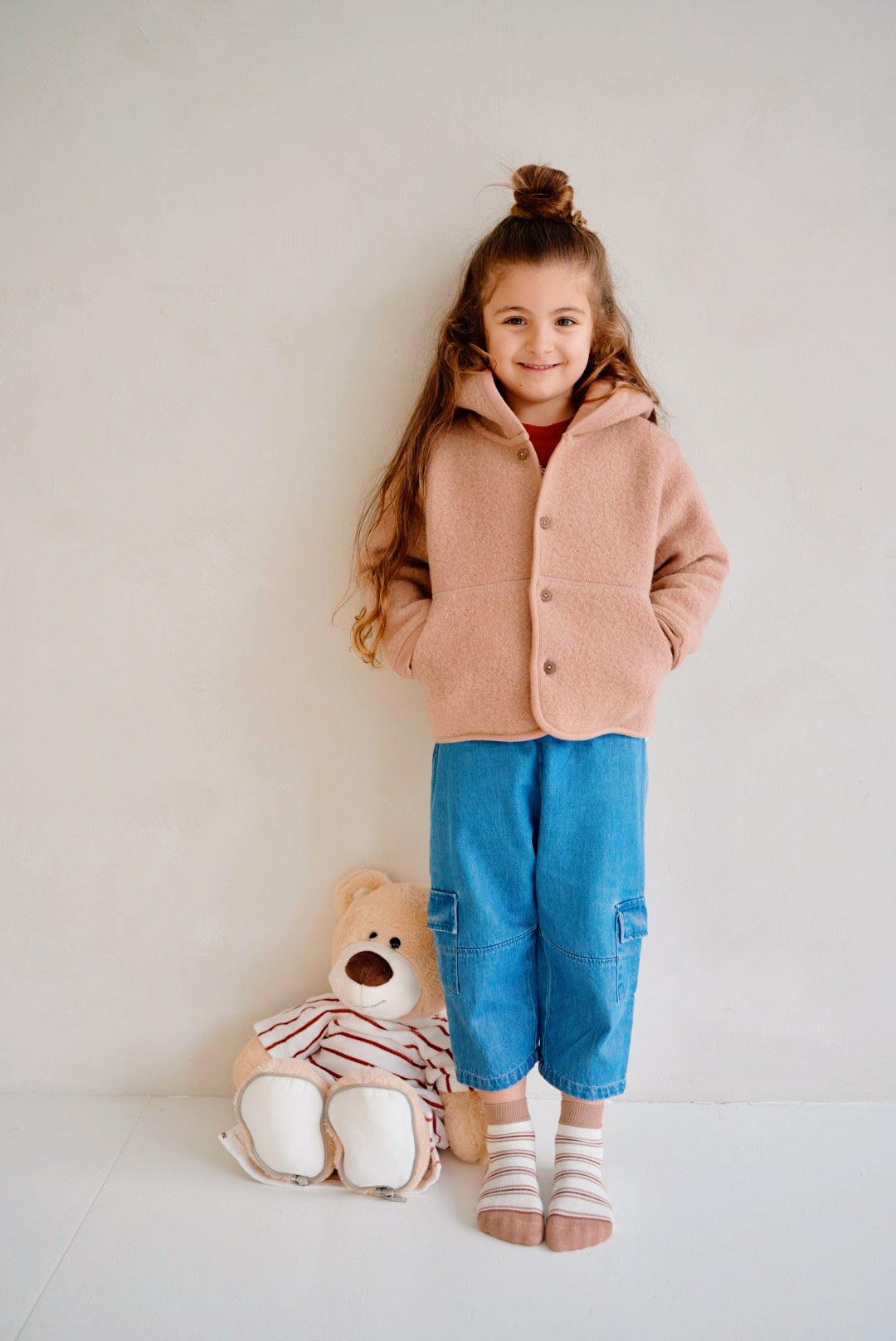 Child wearing blue cotton denim pants with light pink wool jacket