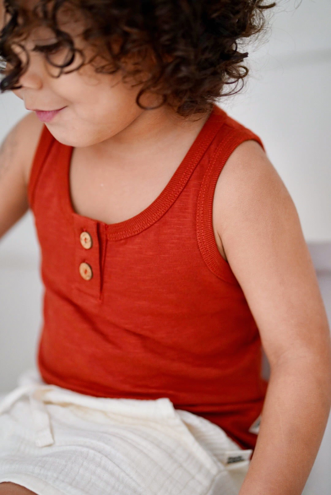 Child wearing cream white cotton muslin shorts with red tank top