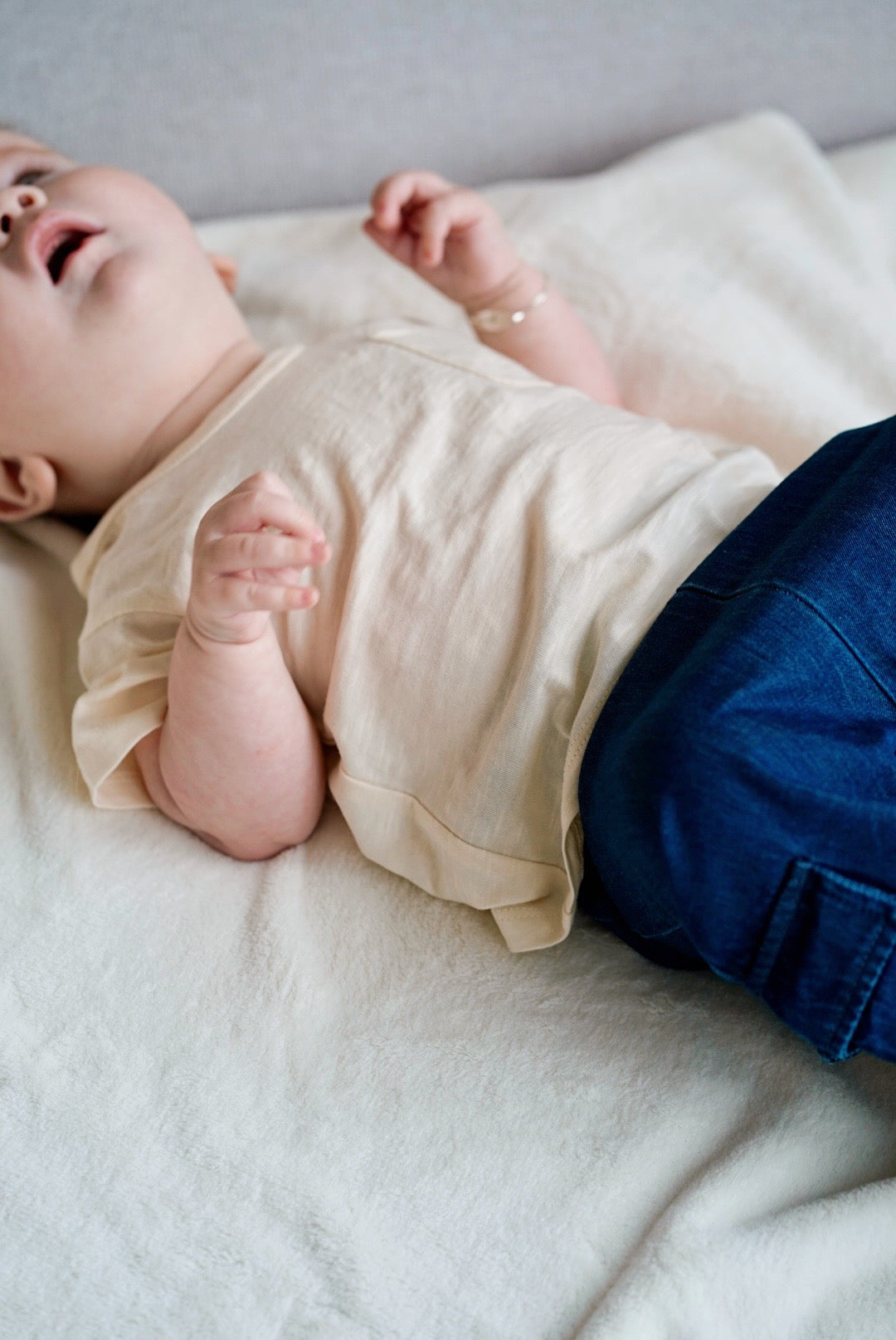 Child wearing cream white muslin short sleeve t-shirt with wooden buttons close-up
