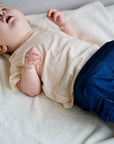 Child wearing cream white muslin short sleeve t-shirt with wooden buttons close-up