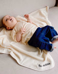Child wearing cream white muslin short sleeve t-shirt with wooden buttons while lying down