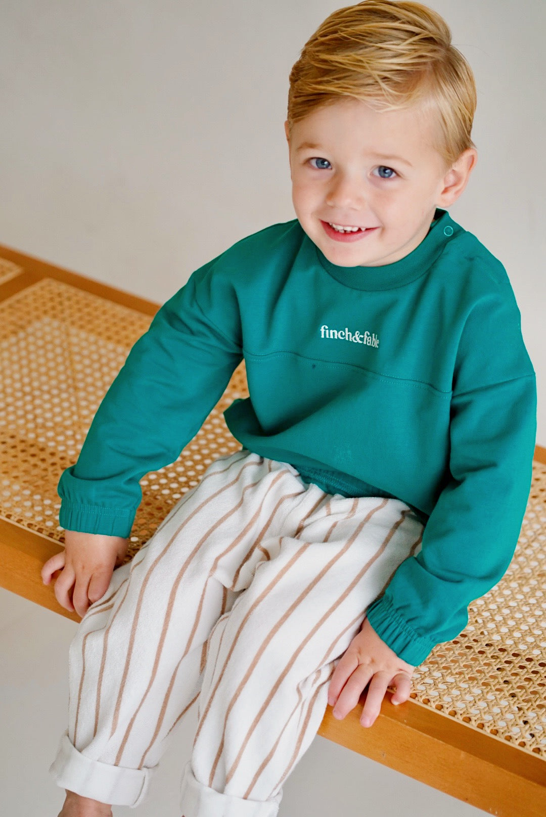 child wearing green fleece sweatshirt with striped pants