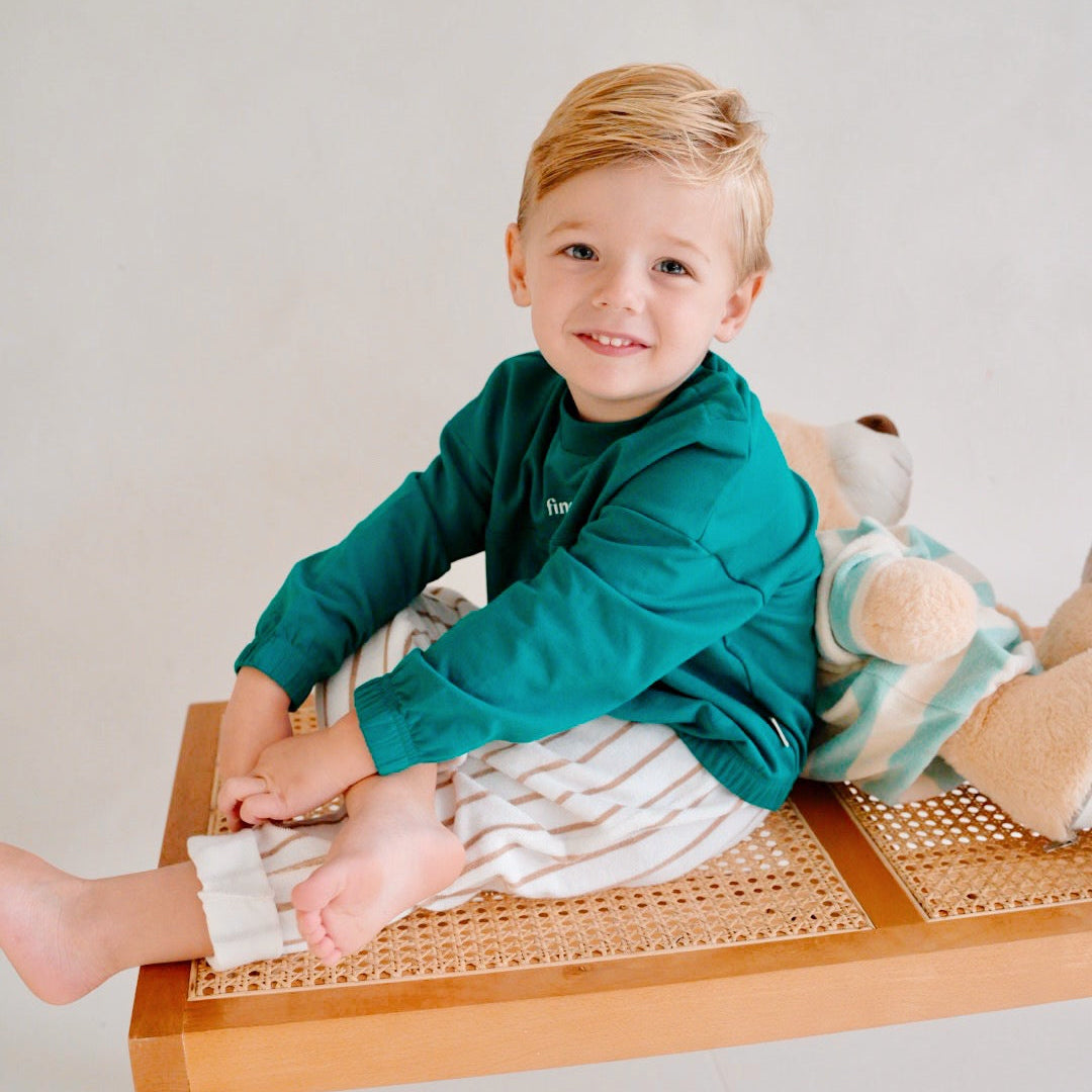 child wearing green fleece sweatshirt with striped pants