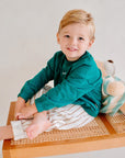 child wearing green fleece sweatshirt with striped pants