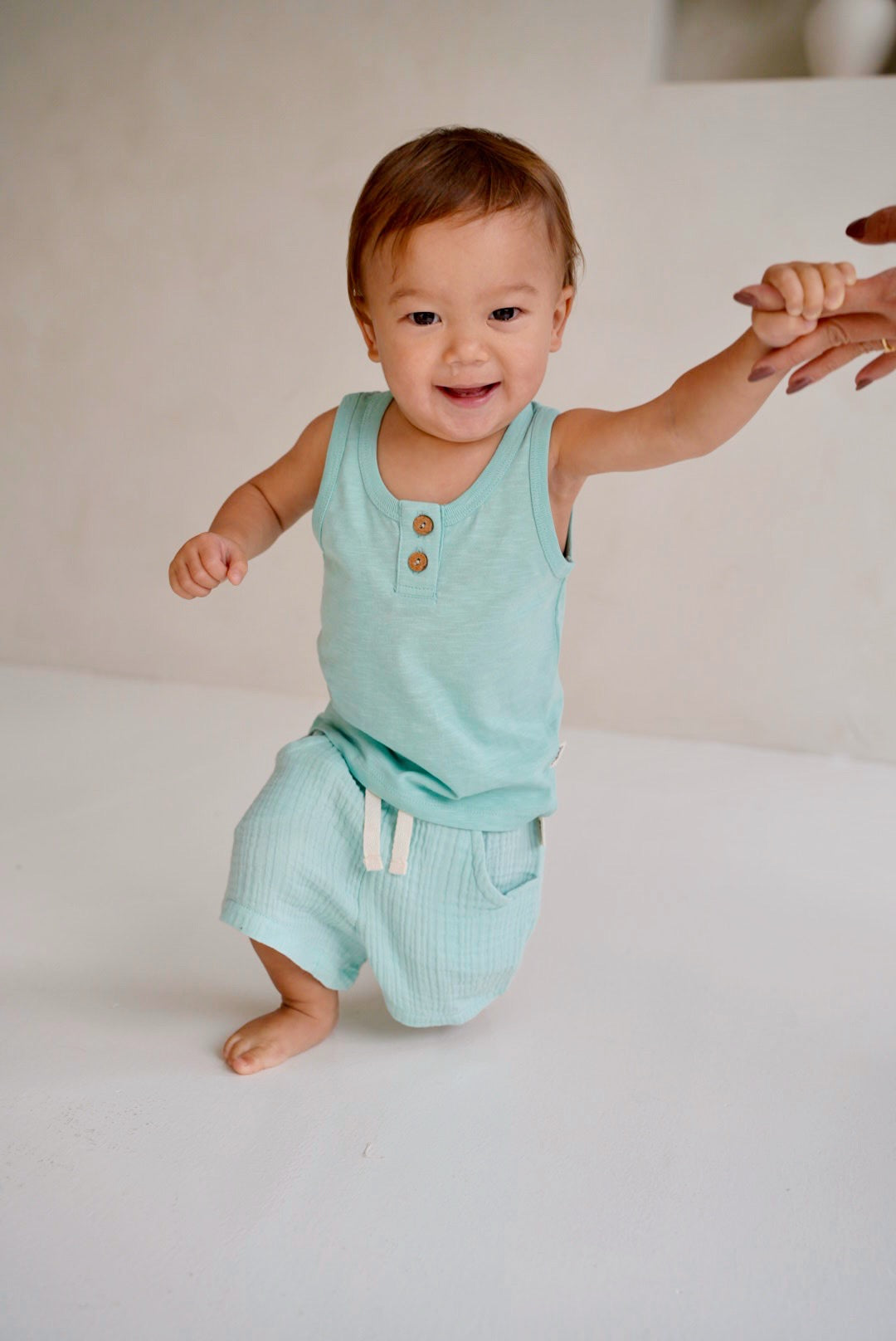 Child wearing light blue cotton slub tank top with wooden buttons front view