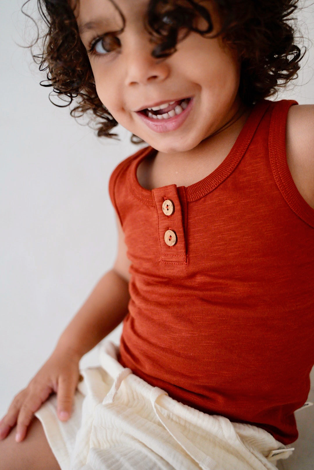 Child wearing red cotton slub tank top with wooden buttons front view