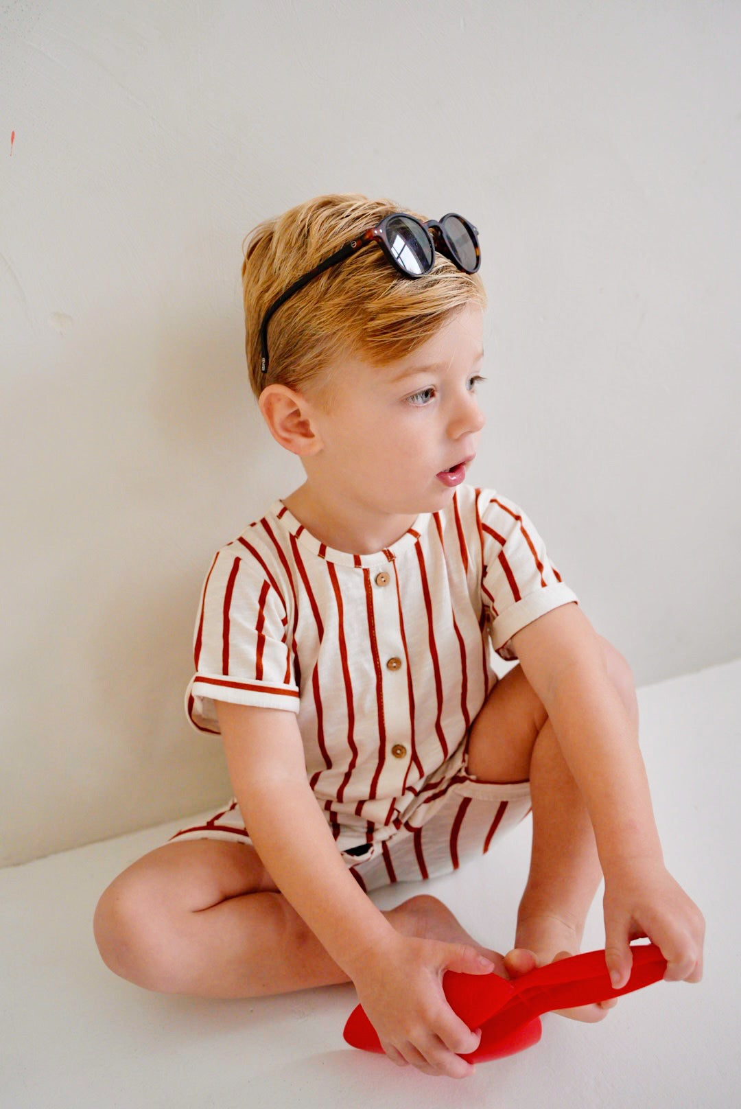 child wearing white cotton playsuit with red stripes close up
