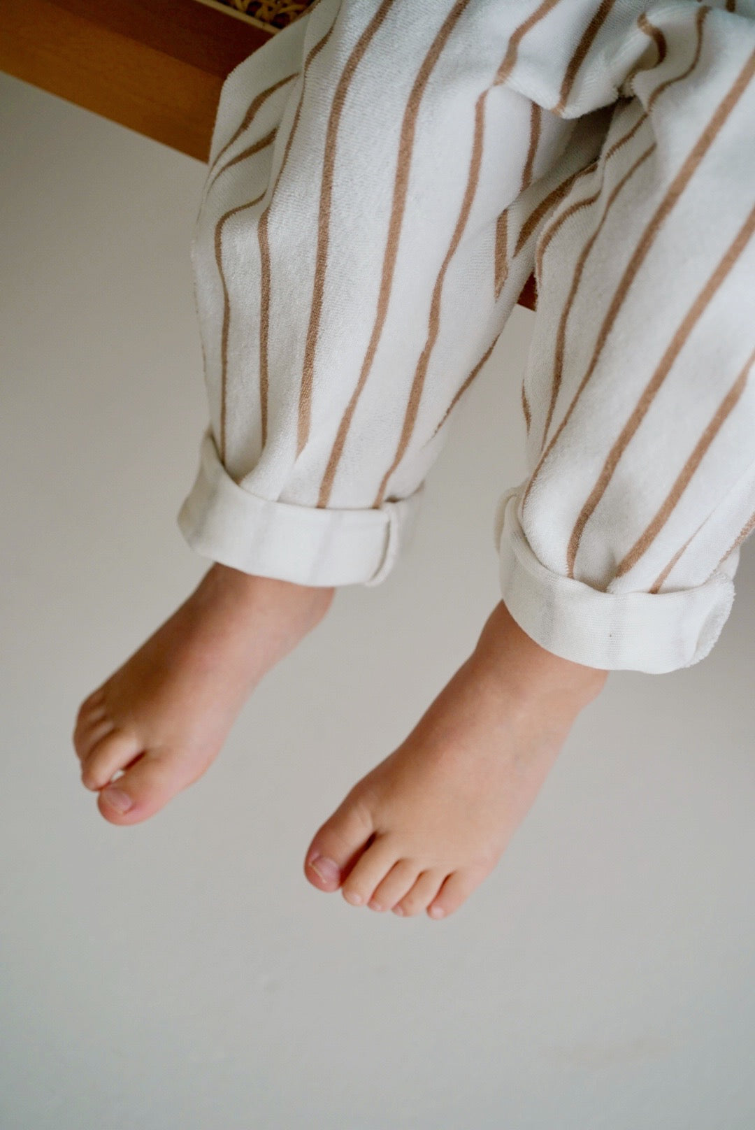 Child wearing white cotton terry pants with beige stripes closeup