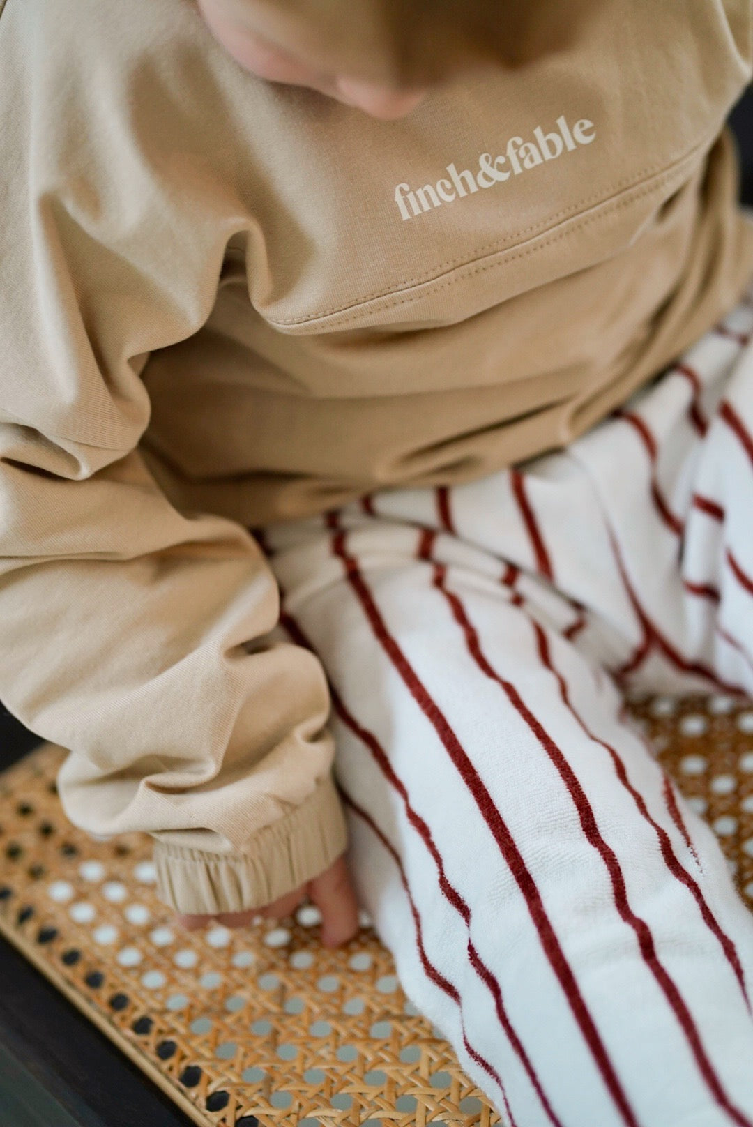 Child wearing white cotton terry pants with red stripes closeup