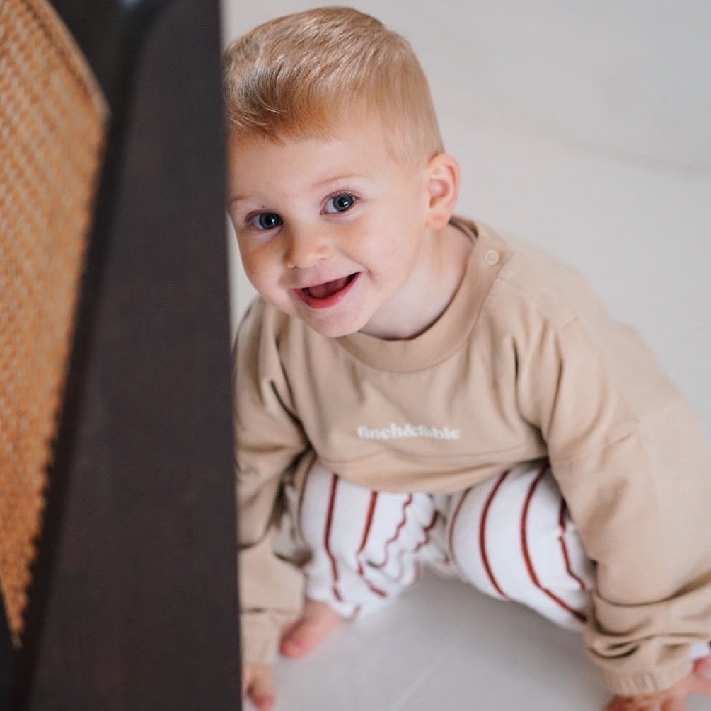 child wearing beige fleece sweatshirt with striped pants close up
