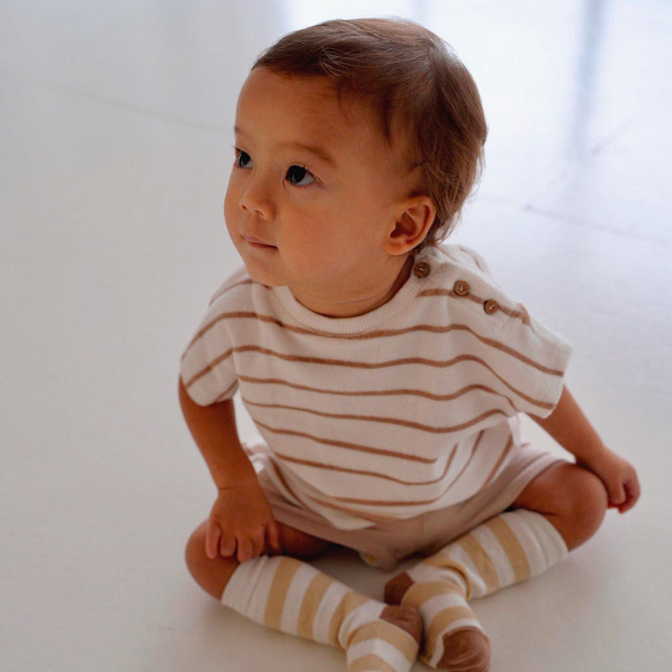 Toddler wearing beige striped cotton terry shirt with wooden buttons front view